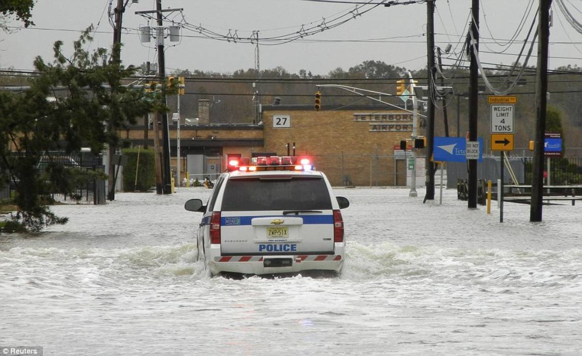 Struggle: A Port Authority Police vehicle makes its way through floodwater covering roads leading toward Teterboro Airport in New Jersey