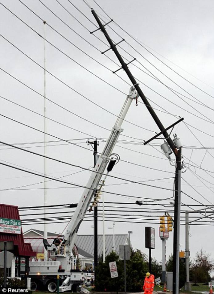 A utility pole, carrying 230,000 volts of electrical power to Atlantic City, is held in place by a truck crane after it snapped from the high winds of Hurricane Sandy in Pleasantville, New Jersey
