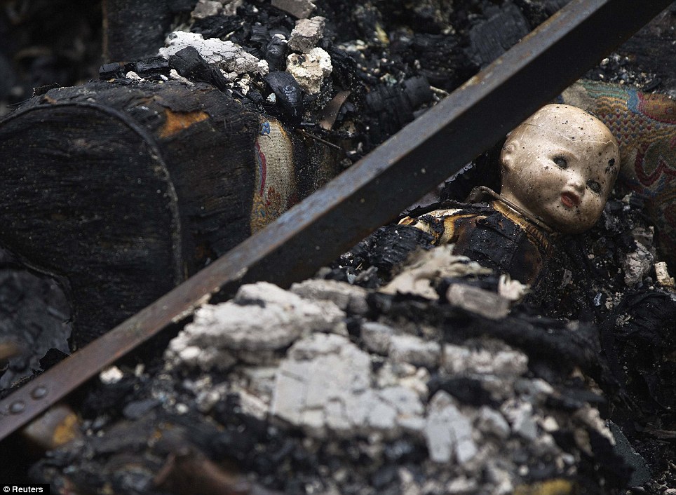Toy: A doll's head can be seen among the charred remains of a house destroyed by fire in the aftermath of the post-tropical storm